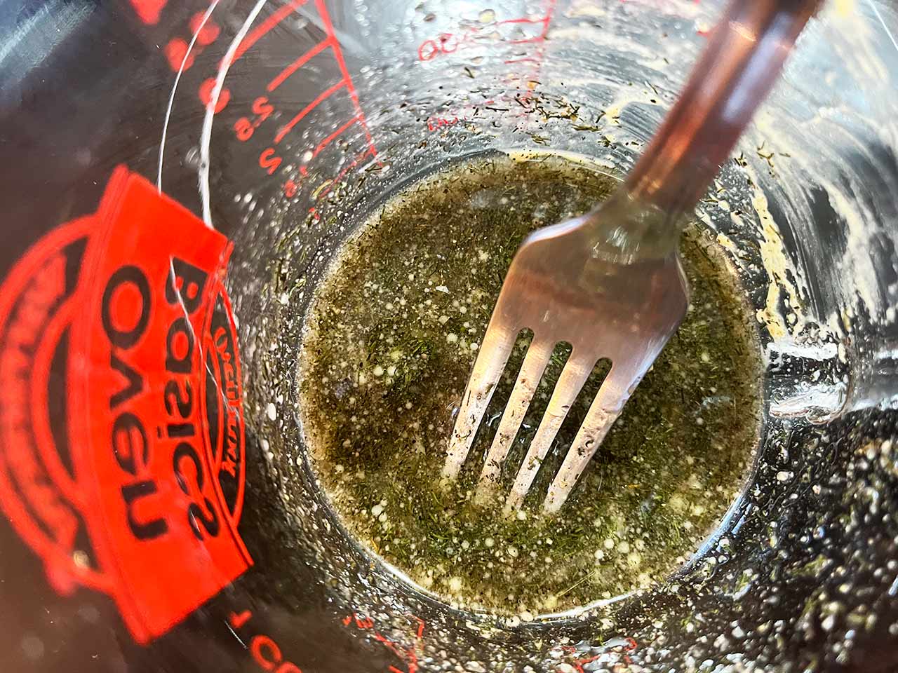 Mixed dressing in a glass measuring cup. A fork rests in the dressing.