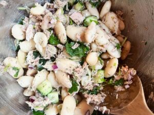 Closeup overhead view of White Bean Salad With Tuna and a wooden spoon.