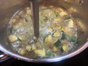 Blending the Creamy Zucchini Soup with an immersion blender in a pot.