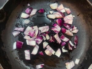 Chopped onions added to oil in a skillet.