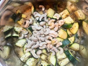 Cashews added to a pot of stock and zucchini.
