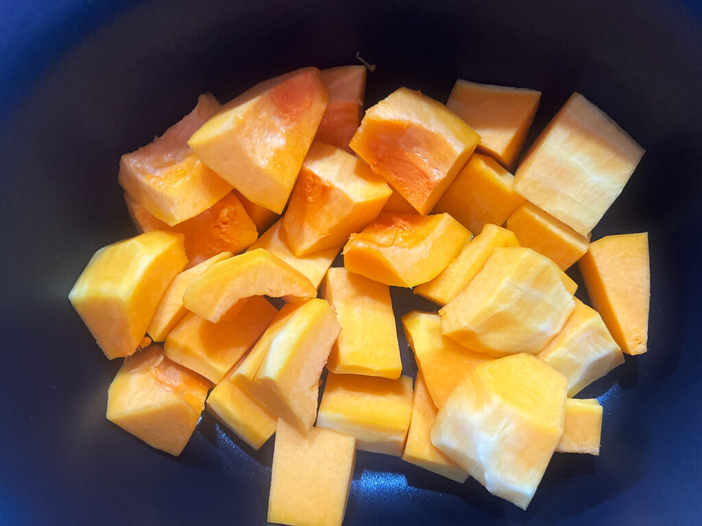 Butternut squash chunks in a slow cooker crock.