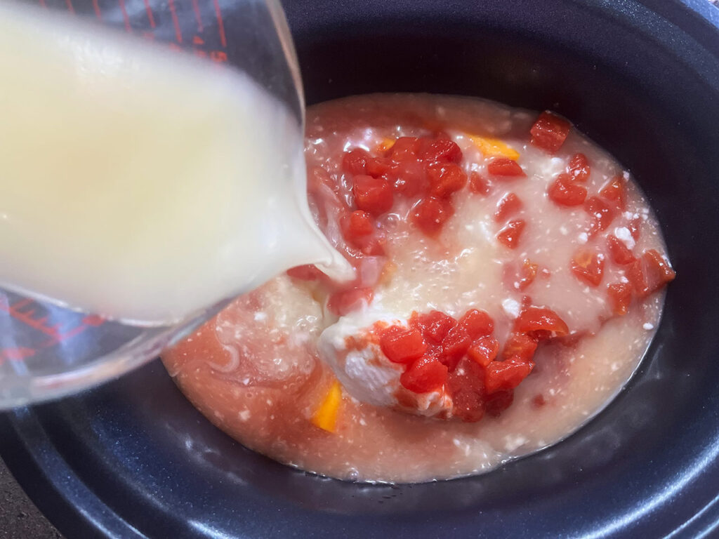 Pouring broth into a slow cooker crock.