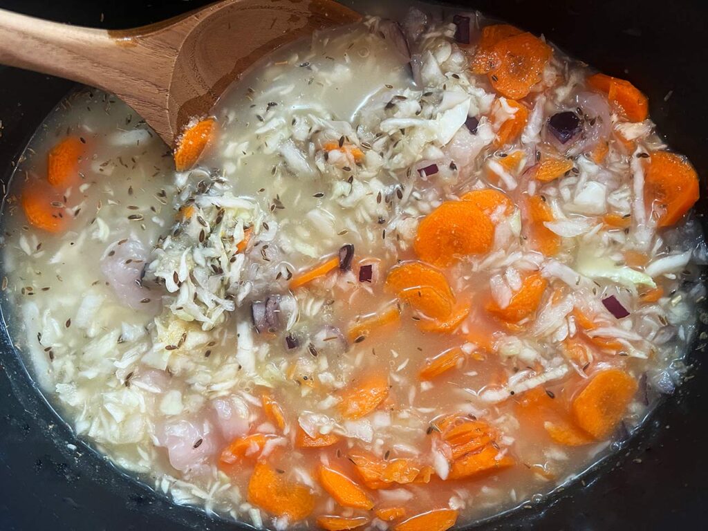 All Slow Cooker Chicken And Cabbage ingredients stirred together in a slow cooker crock just prior to cooking.