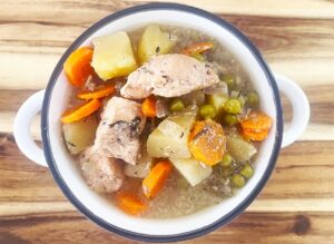 Overhead focus. A white crock filled with Slow Cooker chicken Cobbler Stew.