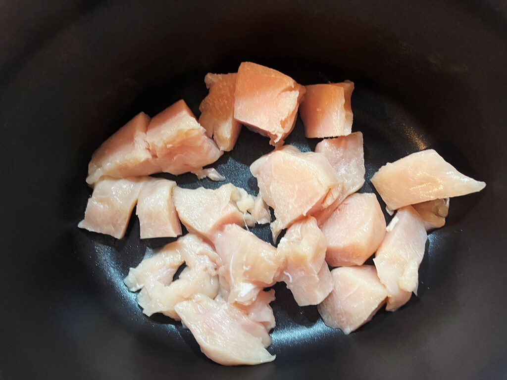 Cut chicken chunks in a slow cooker crock.