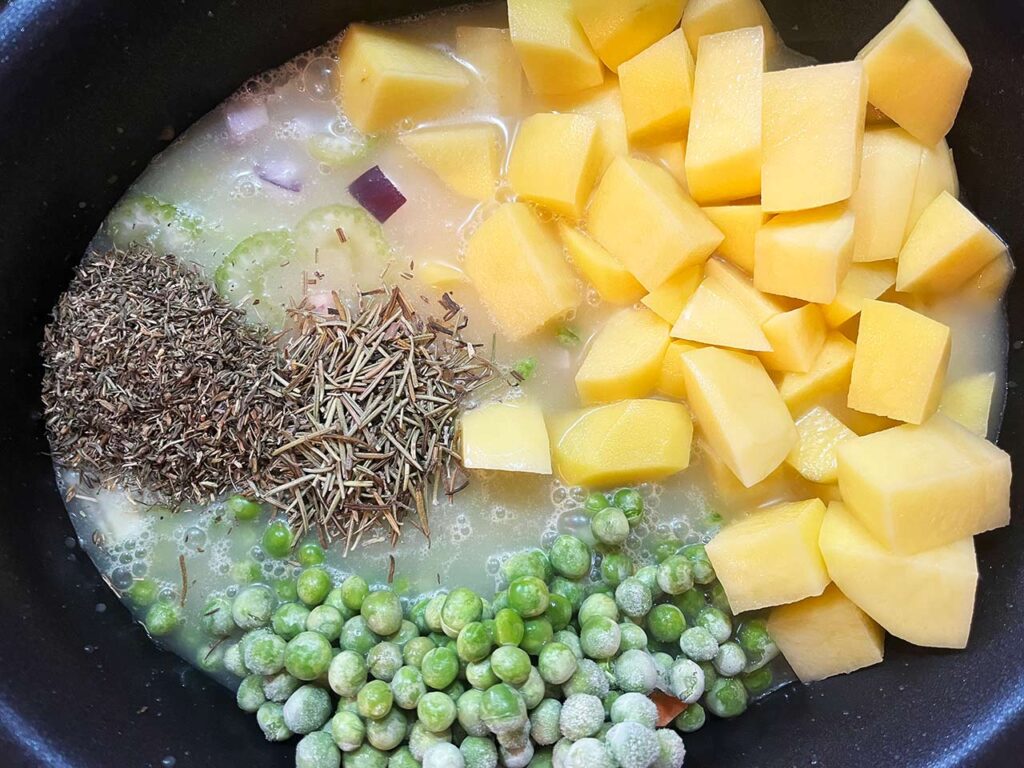 Spices, peas, and broth added to a slow cooker crock.