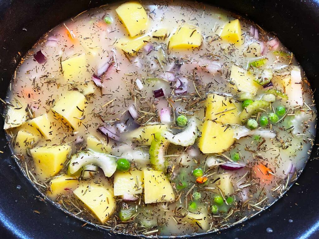 Ingredients for Slow Cooker chicken Cobbler Stew mixed together in a slow cooker crock before cooking.