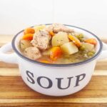Front focus. A white soup bowl filled with Slow Cooker chicken Cobbler Stew.