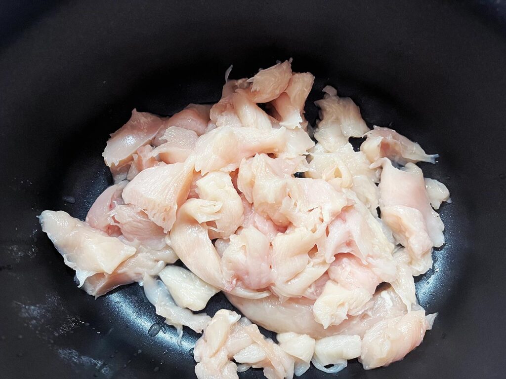 Chicken cut into small pieces, in a slow cooker crock.