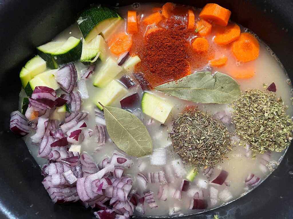 Broth and spices added to the slow cooker crock.