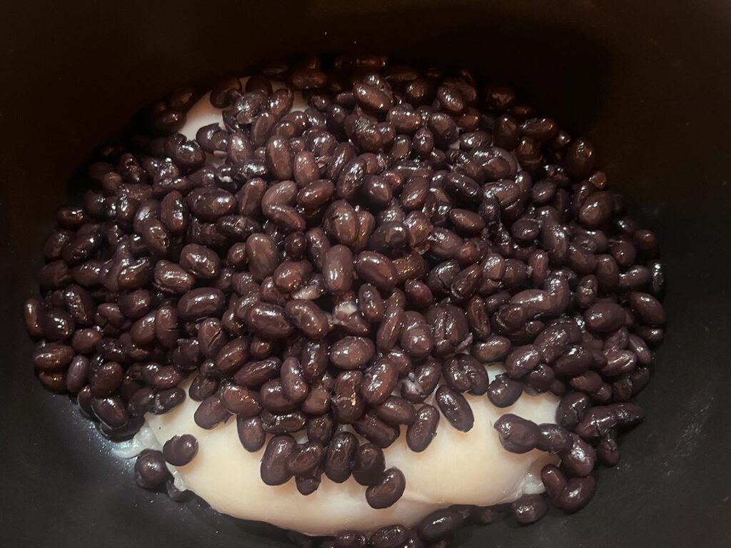 Black beans added to a slow cooker crock.