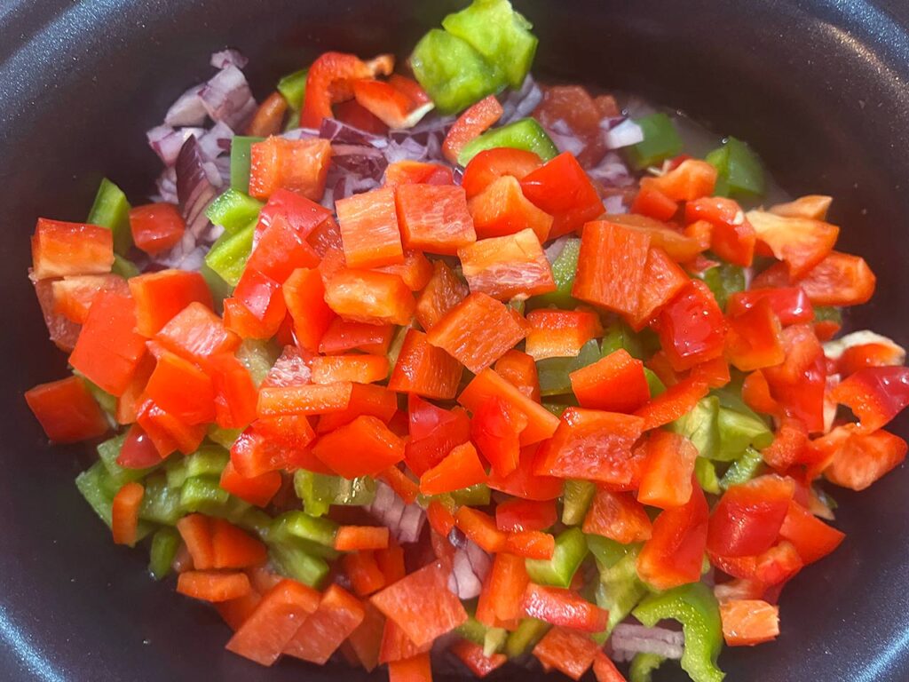 Red ball peppers added to a slow cooker crock for Slow Cooker Chicken Taco Stew.