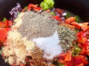 Dried herbs, spices, salt and pepper added to ingredients in a slow cooker crock.