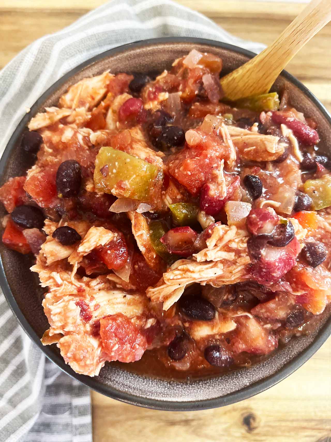 Overhead view of a bowl sitting on a wood surface, filled with Slow Cooker Chicken Taco Stew.