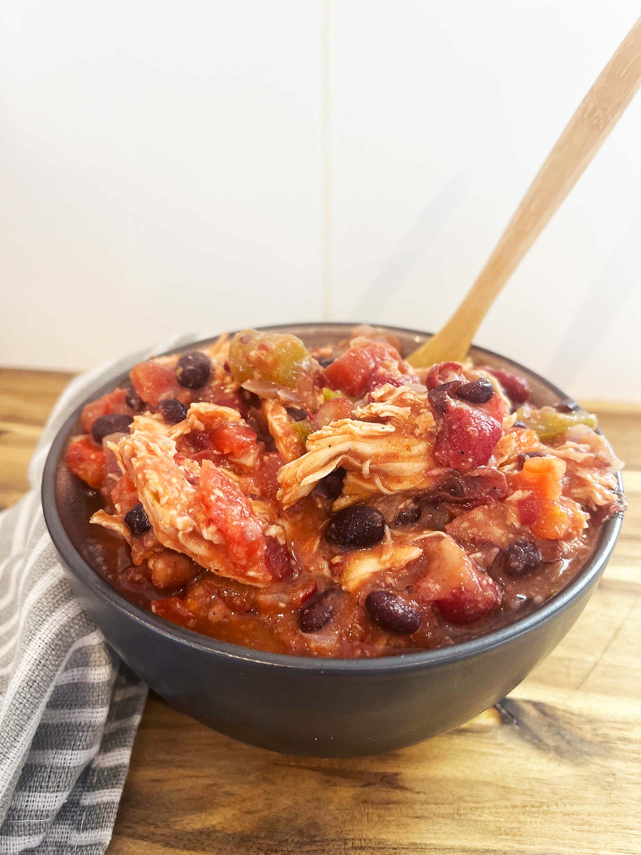 Front view of a black bowl filled with Slow Cooker Chicken Taco Stew.