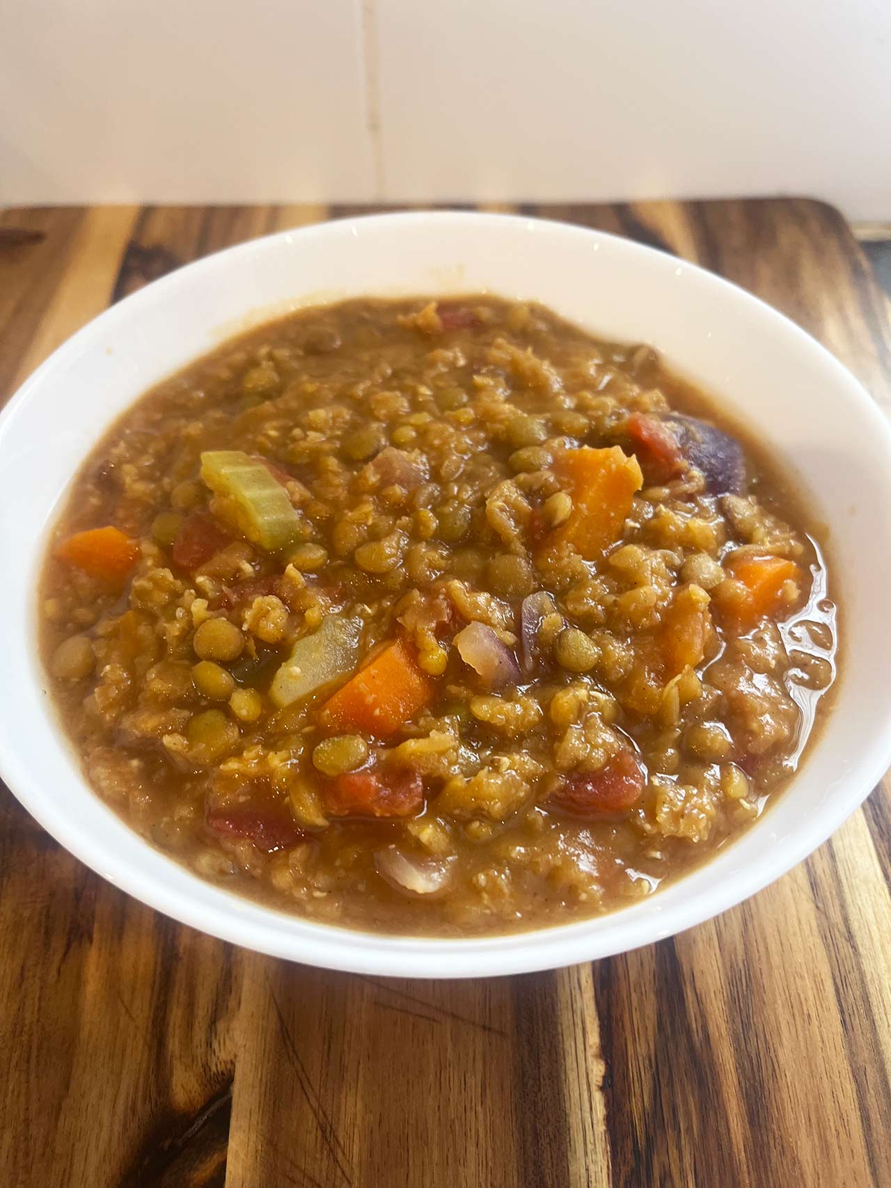 Front view of a white bowl filled with slow cooker lentil stew.