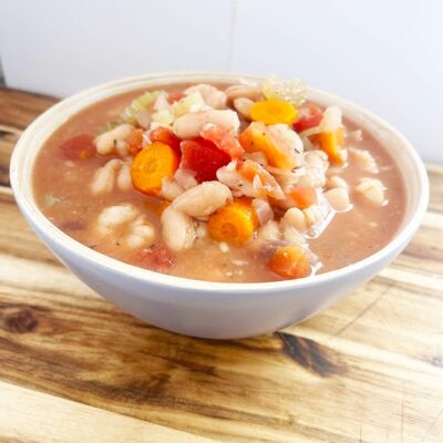 Slightly angled focus. A full bowl of Slow Cooker Shrimp And White Bean Stew.