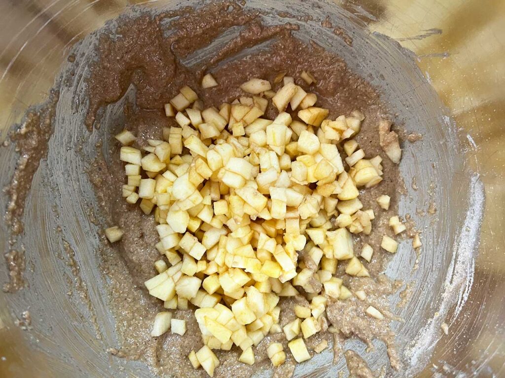 Chopped apple added to cookie batter in a mixing bowl.