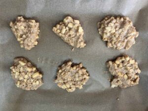 Apple cookie batter spooned onto a parchment-lined baking sheet.