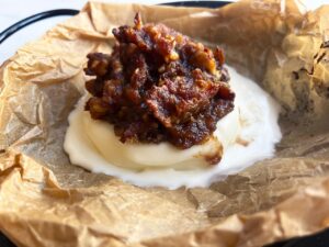 Closeup of a melting round of baked brie with walnut and date topping.