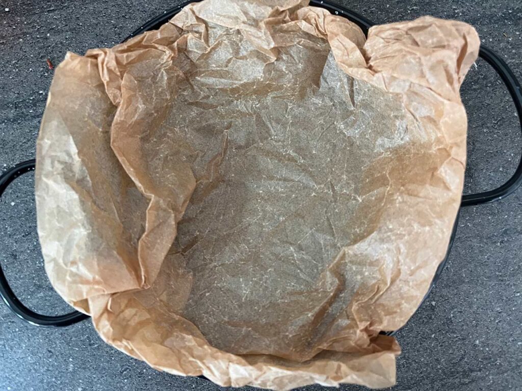 Parchment-lined, oven-safe baking dish. Overhead focus.