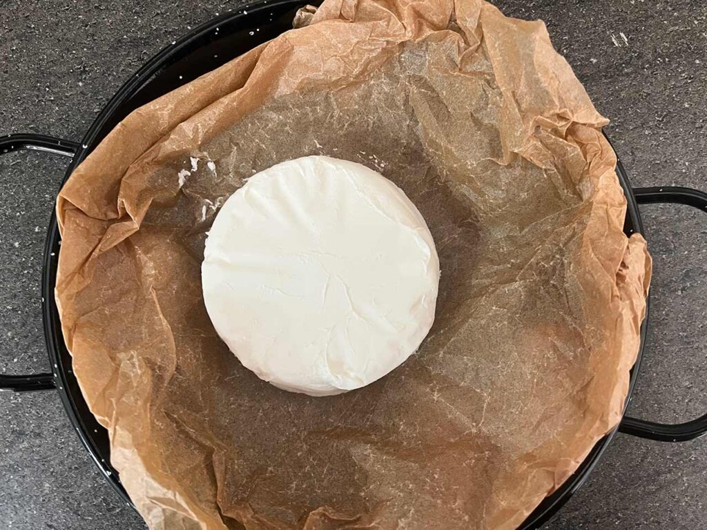 A round of brie placed on the parchment paper.