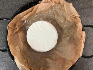 A round of brie placed on the parchment paper.