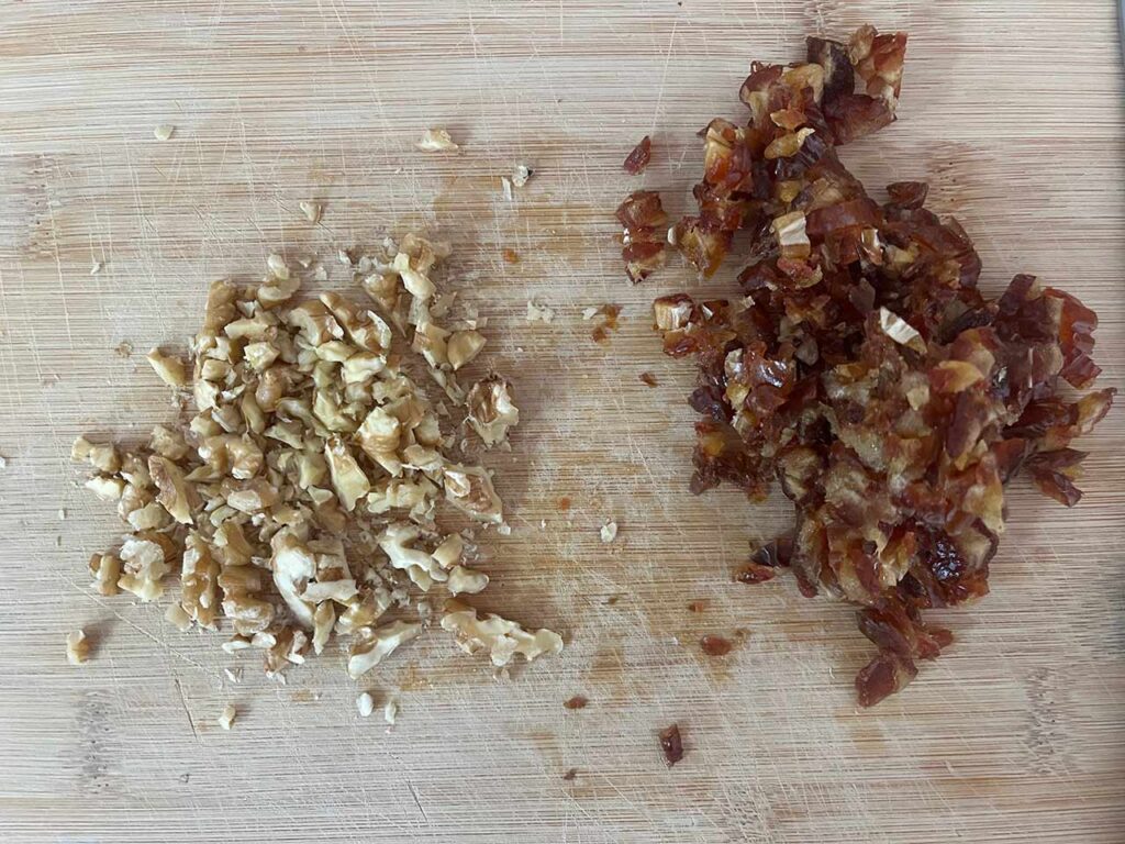 Chopped dates and walnuts on a wood cutting board.