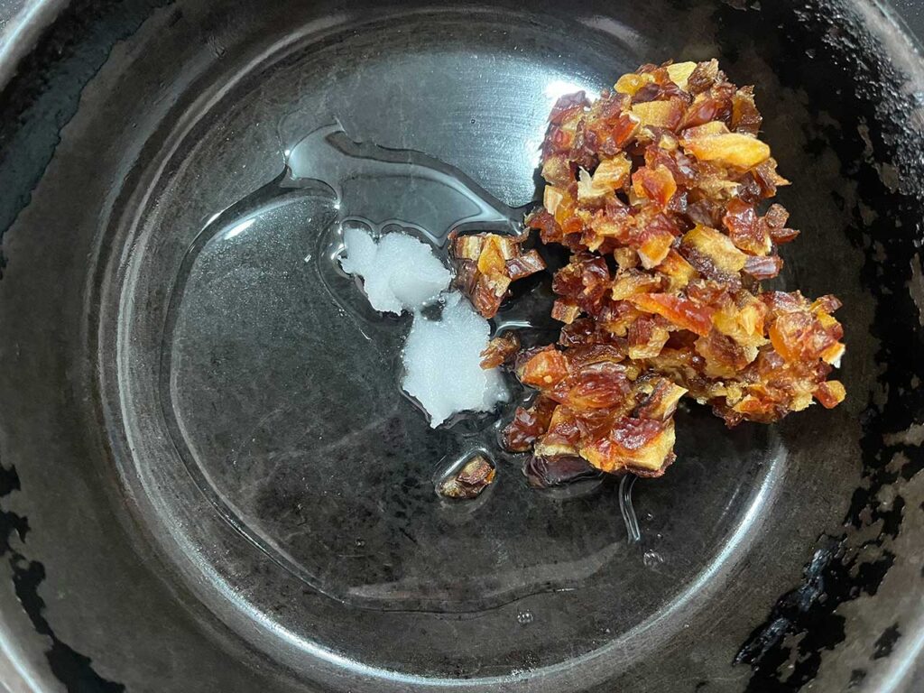 Oil melting in a skillet with chopped dates added.