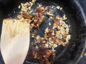 Adding chopped walnuts to date paste in a skillet.