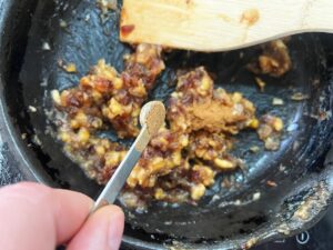 Adding spices to the date and walnut mixture.
