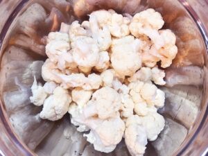 Overhead focus. A mixing bowl half full of cauliflower florets.