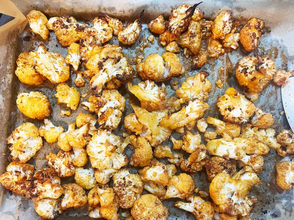 Roasted cauliflower florets on a baking pan after roasting.