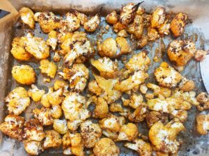 Roasted cauliflower florets on a baking pan after roasting.