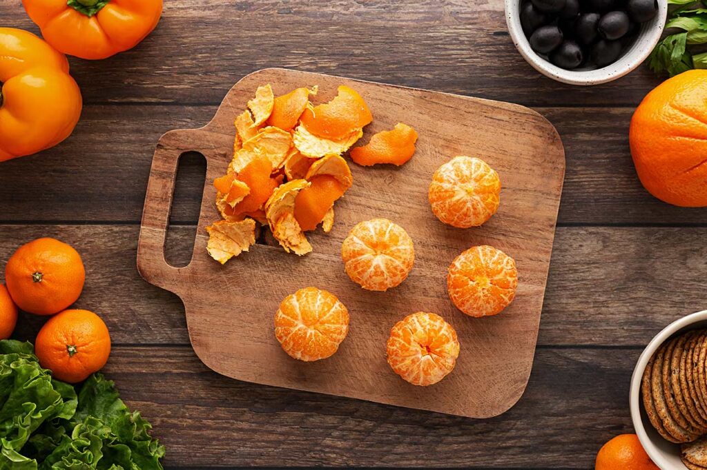 Peeled mandarins on a wood cutting board.