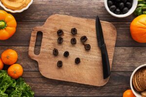 Black olives cut in half on a cutting board.