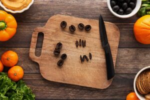 A black olive cut into thin strips on a cutting board.