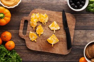 Cheese slices cut into the shape of autumn leaves on a cutting board.