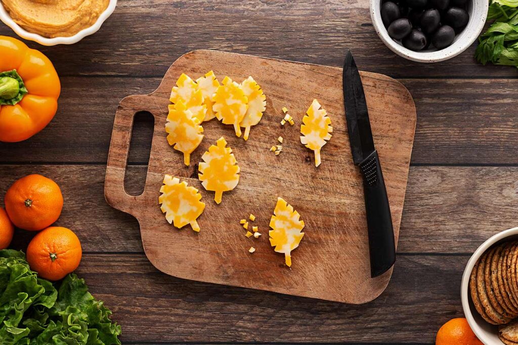 Notches cut into cheese slices to make autumn leaf shapes.