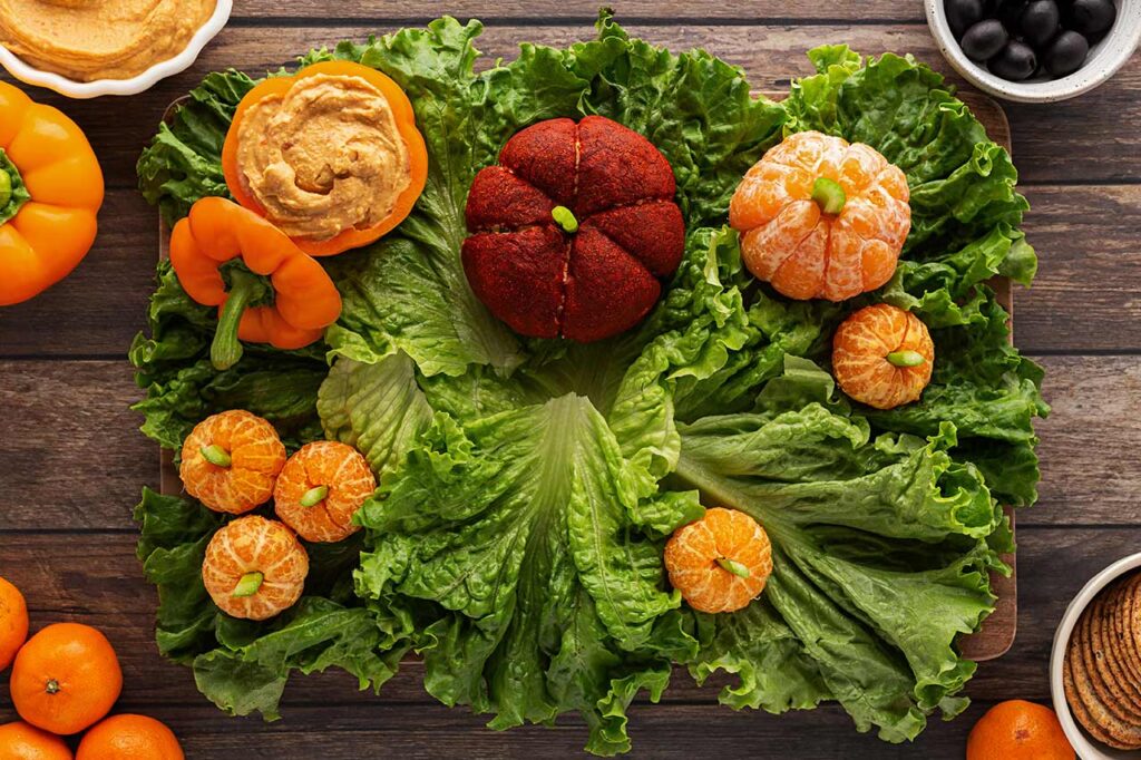 A cheese ball pumpkin placed in the top middle of the charcuterie board.