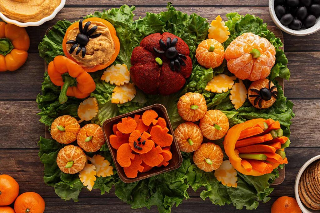 A small container of pumpkin-shaped carrot slices placed in the lower middle of the board.