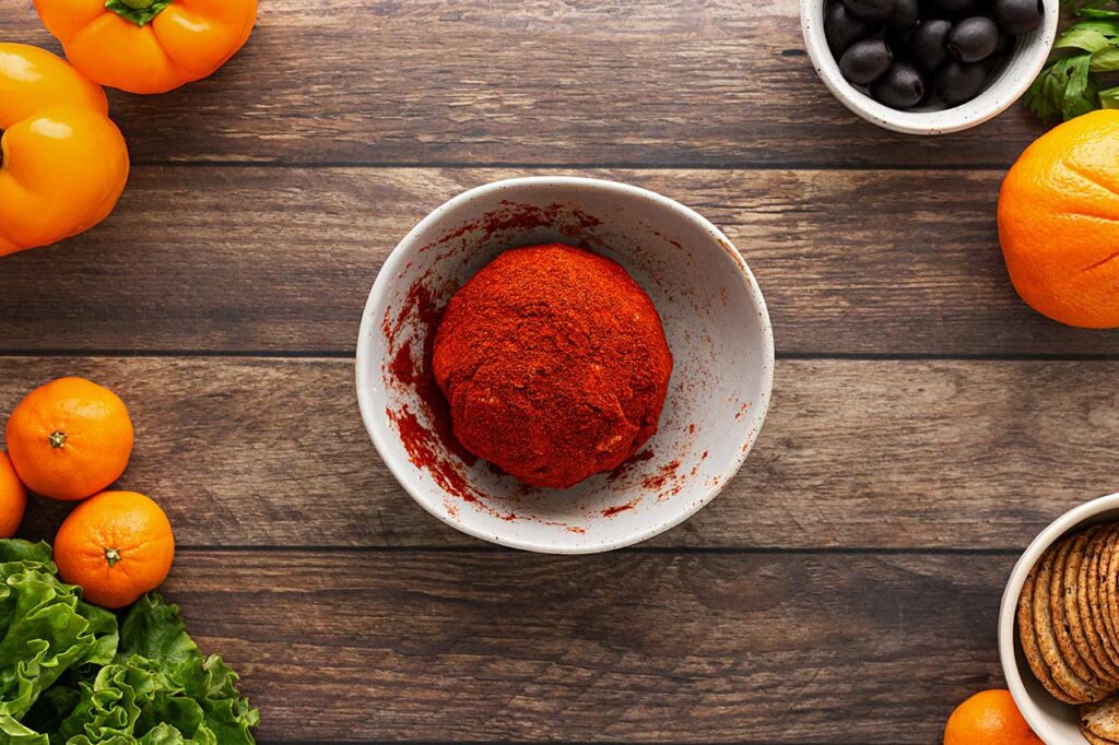 A cheese ball fully covered in ground paprika. Overhead focus.