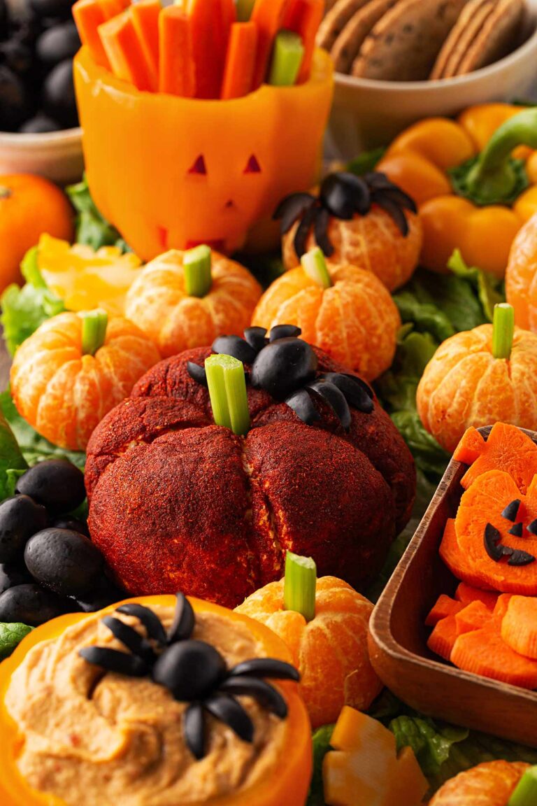 A cheese ball colored with paprika and shaped into a pumpkin with a celery stem.