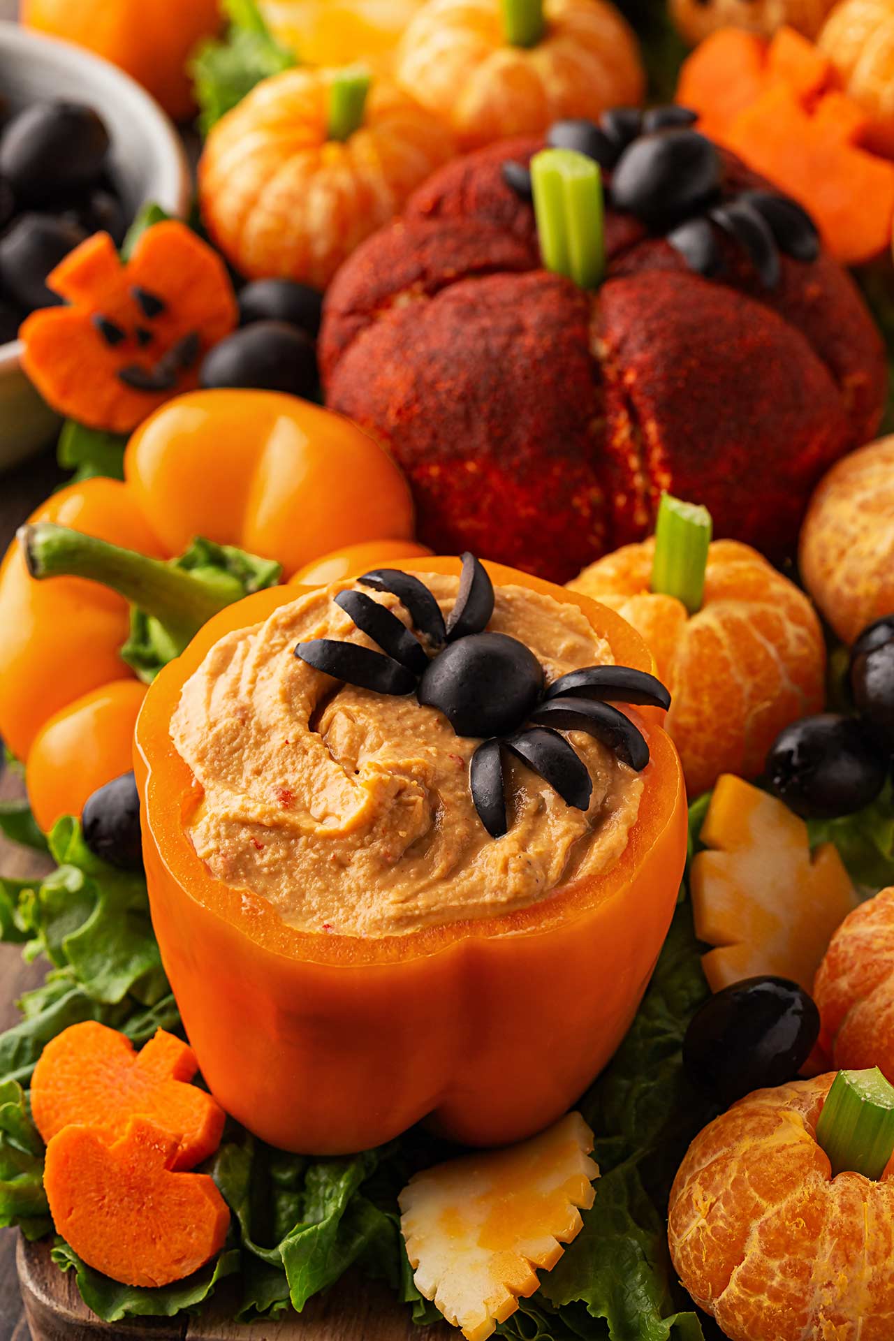 An orange bell pepper filled with hummus and topped with an olive spider.