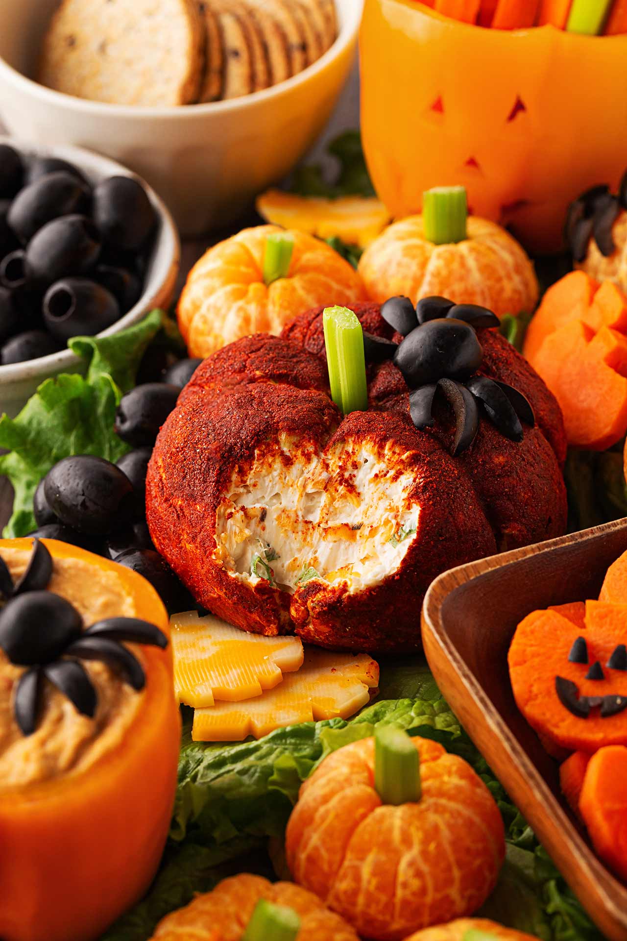 A closeup of the pumpkin-shaped cheese ball with a bit scooped out.