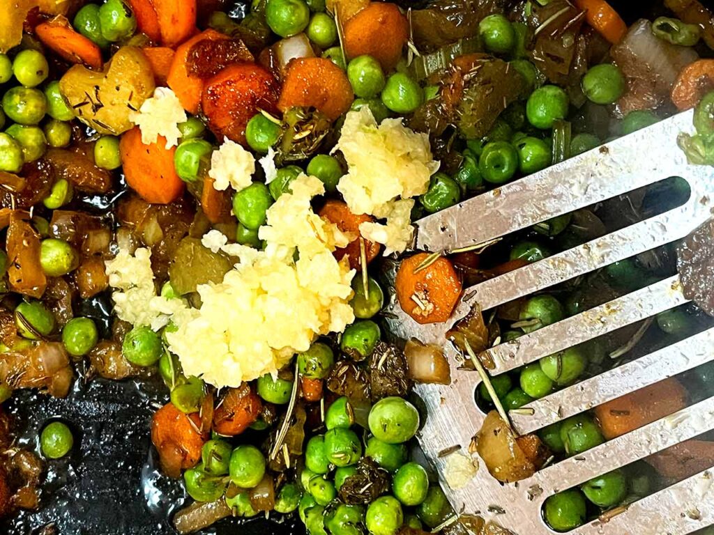 Fresh, pressed garlic added to veggies in a skillet.