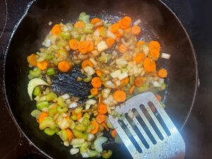 Sliced carrots, celery, and onions saut&eacute;ing in a skillet.