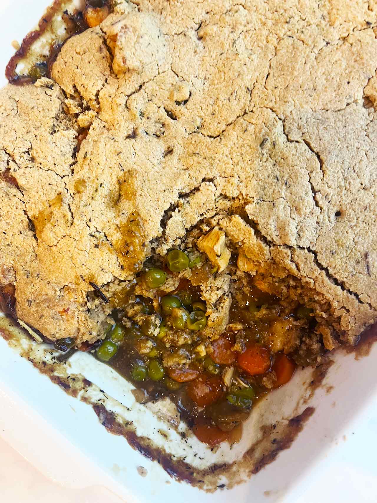 Overhead focus. The chicken cobbler casserole with a portion missing.