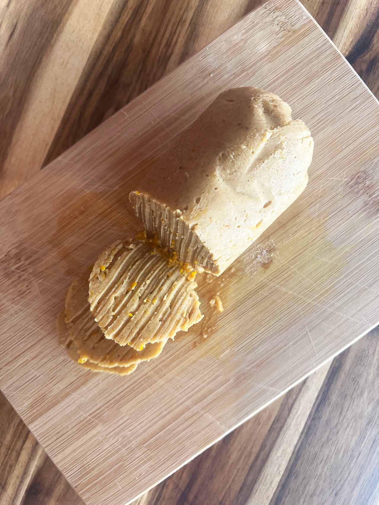 Overhead focus. A compound butter log on a cutting board with three slices laying in front of it.